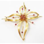 A 2 3/4" yellow metal stylized floral brooch, set with small rubies