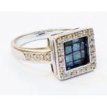 A marked 14k/585 white metal ring, set with paved blue diamonds in a recessed square panel with