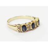 A hallmarked 375 gold ring, set with three sapphires interspersed with pairs of tiny diamonds