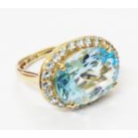 A hallmarked 375 gold ring, set with large oval pale blue topaz within a topaz border