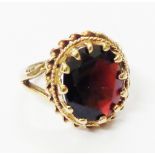 A marked "9" yellow metal ring, set with oval garnet panel