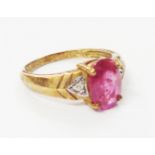 A marked 375 gold ring, set with central oval rubellite flanked by tiny diamonds with certificate