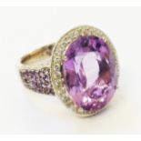 A hallmarked 750 white gold ornate ring, set with large central oval amethyst within a diamond