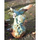 A painted cast iron garden fairy sat weeping on a ball of flowers