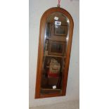 An early 20th Century stained walnut framed narrow dome top wall mirror, with bevelled plate