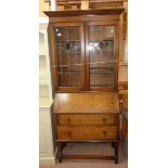 A 3' 3" early 20th Century oak bureau bookcase with decorative leaded glass doors to bookcase top,