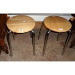 A pair of modern stools with polished blonde wood tops and chrome plated legs