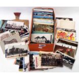 A box and wallet containing a collection of early to mid 20th Century postcards including posed
