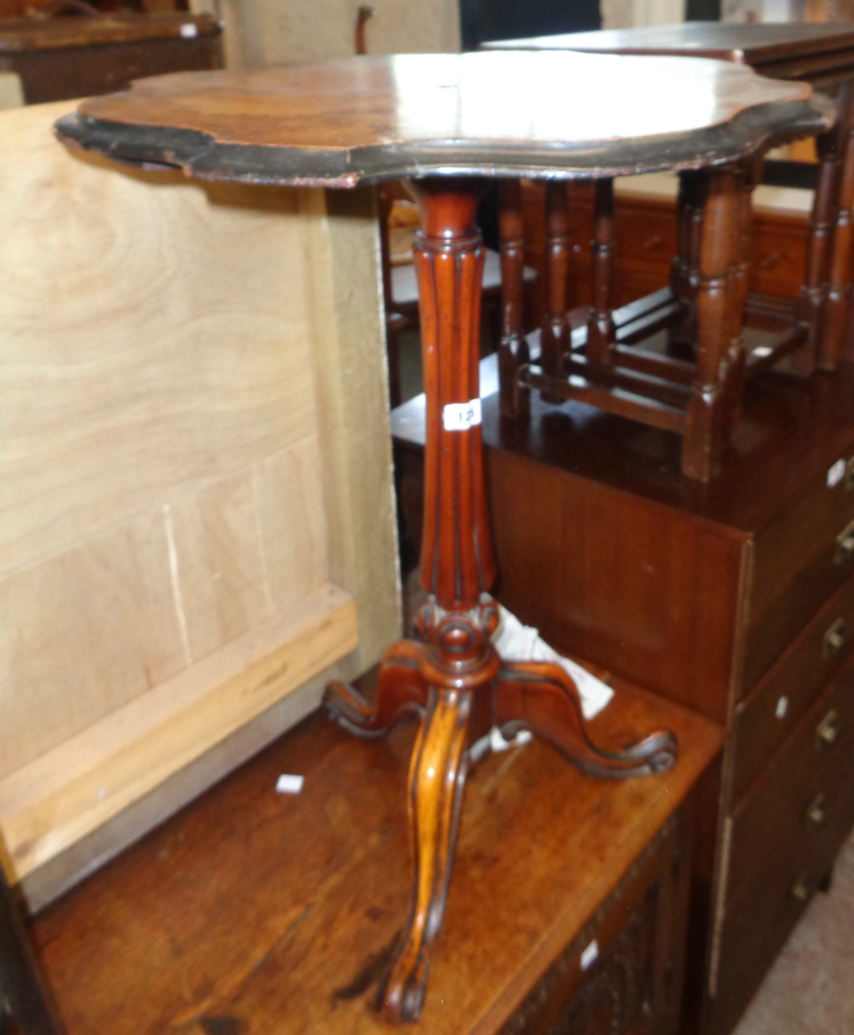 A 22" Victorian walnut pedestal table with shaped top, set on turned and reeded pillar with tripod