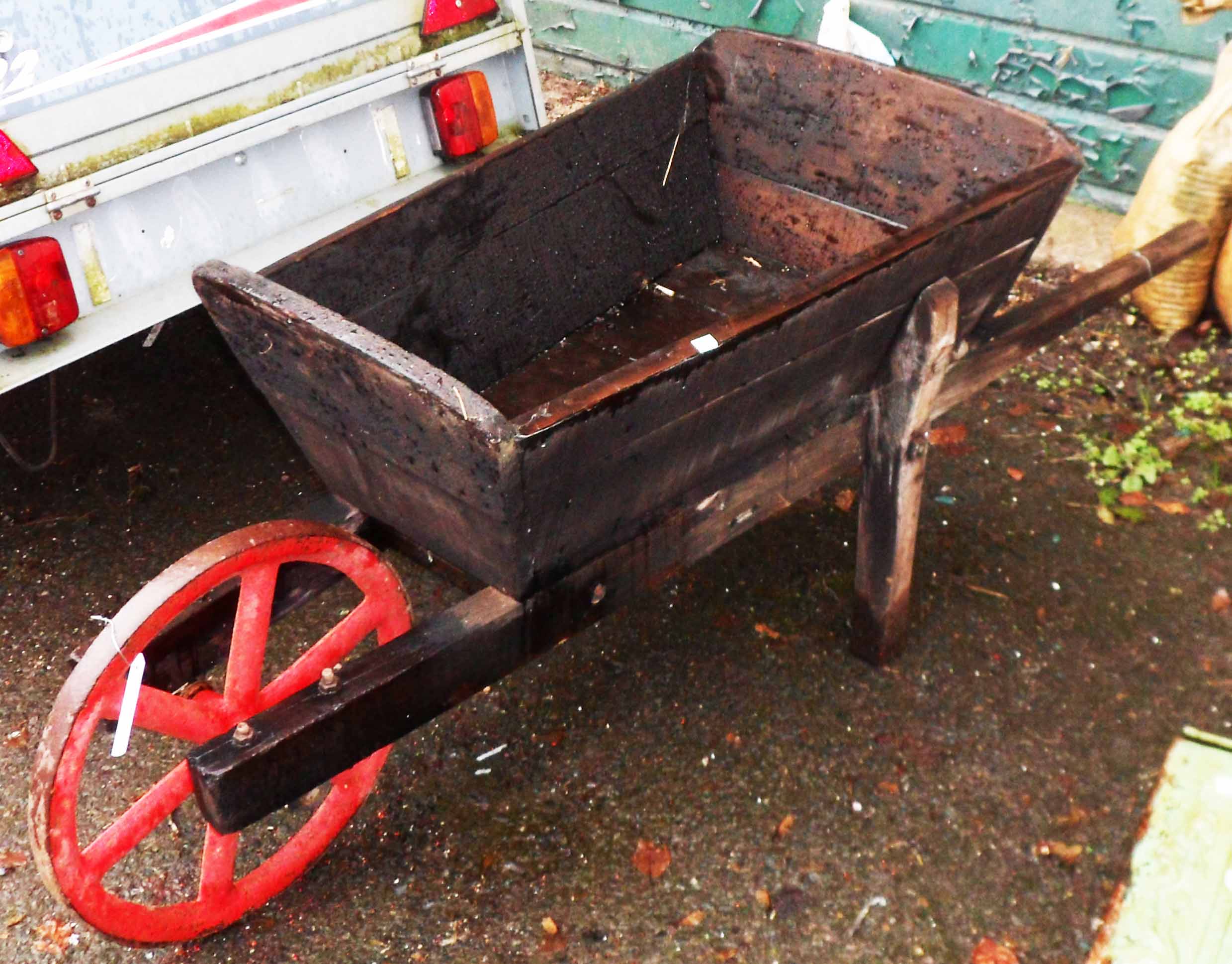 A vintage wooden wheelbarrow with large cast iron wheel