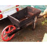 A vintage wooden wheelbarrow with large cast iron wheel