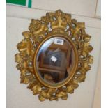A small ornate gilt plaster framed oval wall mirror with grape vine decoration