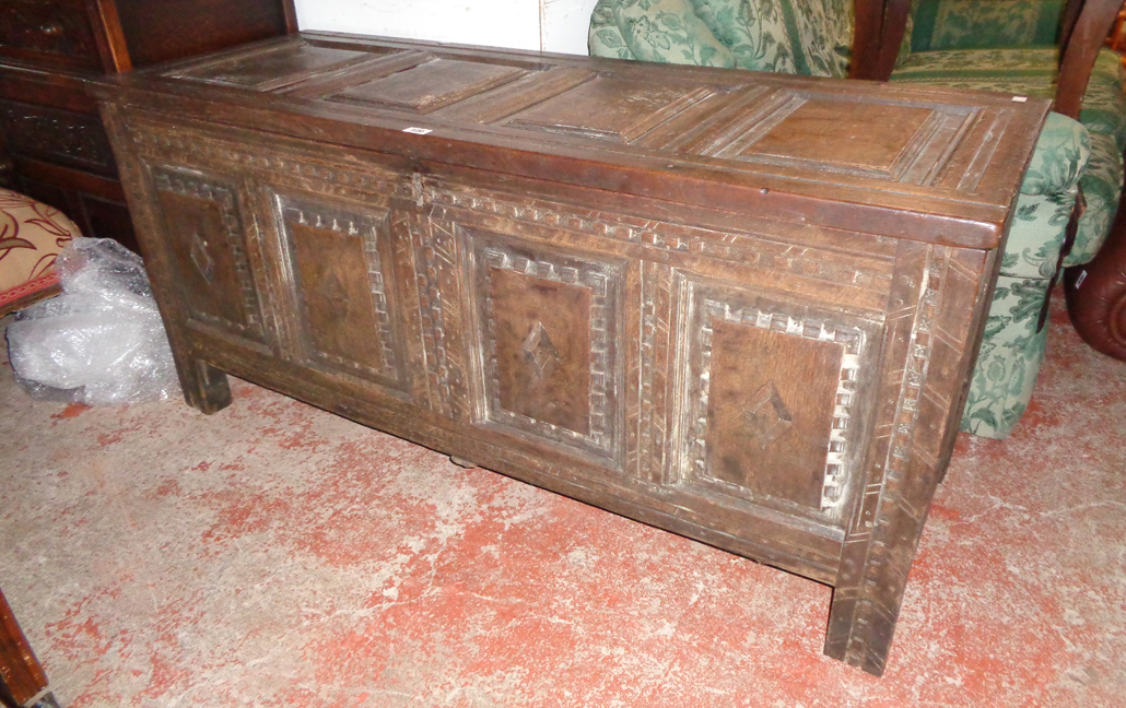 A 4' 11" antique oak four panel coffer with later carved decoration to front, set on block feet