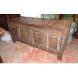 A 4' 11" antique oak four panel coffer with later carved decoration to front, set on block feet