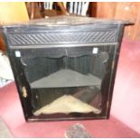 A 25" old stained wood wall mounted corner cabinet with serpentine top and glazed panel door