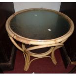 A 23" diameter cane framed two tier occasional table with glass inset surfaces