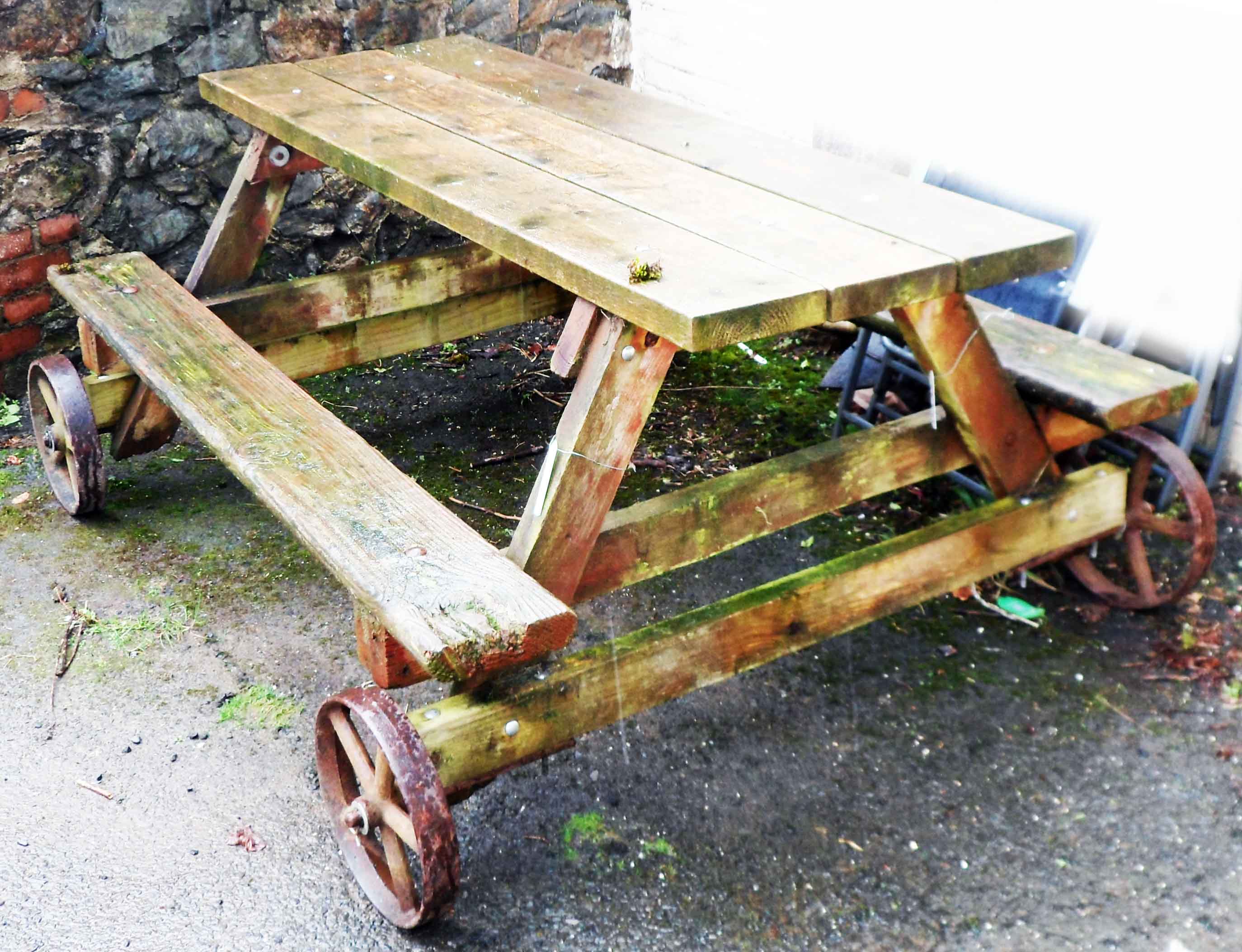 An large garden bench table on cast iron wheels