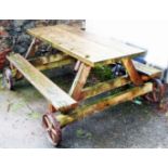 An large garden bench table on cast iron wheels