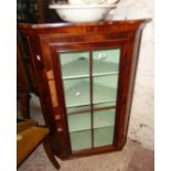 A 30 1/4" antique mahogany wall mounted corner cabinet with shelves enclosed by a glazed panel