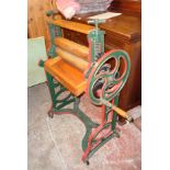 An old painted cast iron mangle with wooden rollers and folding action