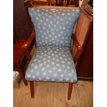 A retro armchair with polished teak armrests and blue repeat pattern upholstery, set on splayed