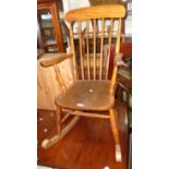 An antique high stick back rocking chair with solid elm seat and ring turned supports