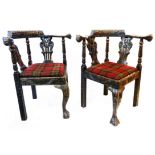 A pair of Victorian stained oak corner elbow chairs with profuse carved decoration, mask terminals