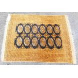 An Eastern handmade rug with two rows of elephant gul medallions, within an orange and copper