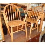 A pair of Ercol style light elm seated elbow chairs with hoop stick backs and simple turned