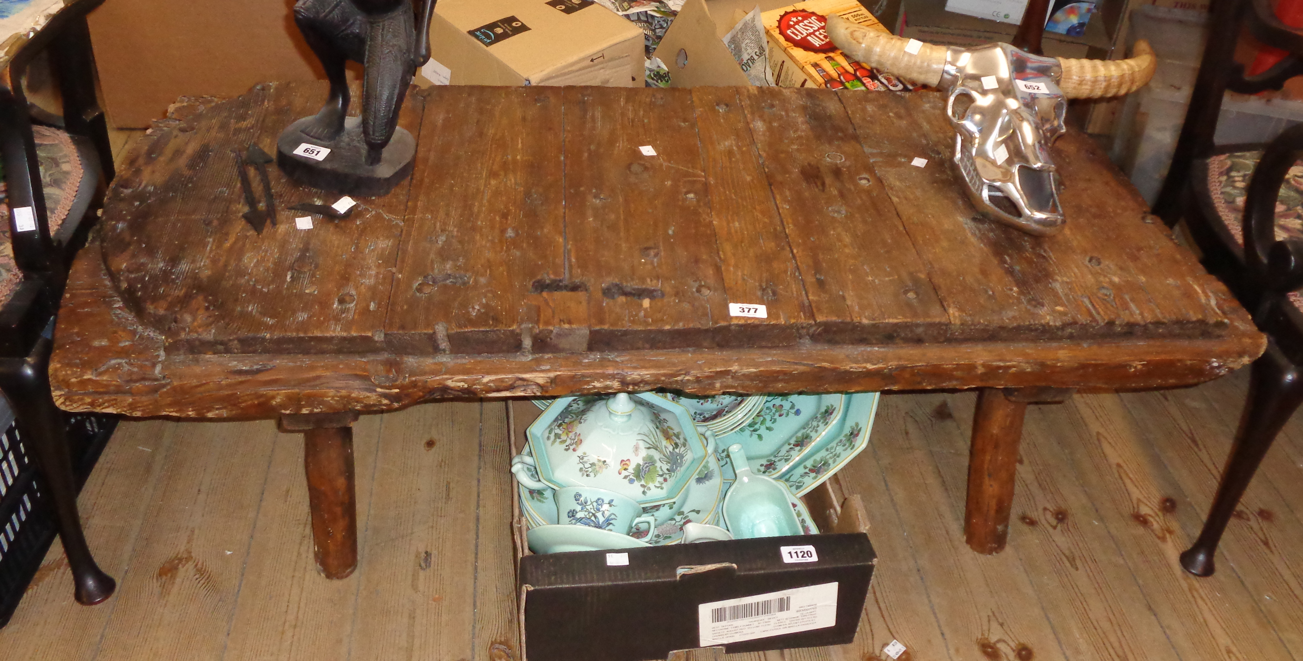 A 3' 4" coffee table made from an antique iron studded planked wood door, set on rustic supports