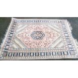 A 20th Century Middle Eastern handmade wool rug with central medallion on faded pink ground,