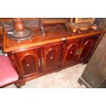 A 4' 7 1/2" reproduction polished walnut effect sideboard with two pairs of panelled doors enclosing