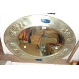 An early 20th Century Arts & Crafts style embossed metal clad framed bevelled oval wall mirror