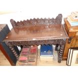 A 3' 5" Victorian carved oak side table with decorative raised back and apron, set on bobbin