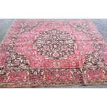 A 20th Century machine made Turkish pattern rug with medallions and profuse floral scrolls on red
