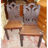 A pair of 19th Century carved oak hall chairs with double headed eagle pattern backs and barley
