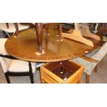 A 6' 5" mahogany and rosewood cross banded oval tilt-top dining table, set on turned pillar and