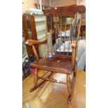 A 20th Century stained mixed wood high stick back rocking chair with laminated seat panel and turned