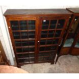 A 4' old stained oak book cabinet with shelves enclosed by a pair of beaded glazed panel doors (