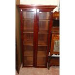 A 29" early 20th Century stained walnut book cabinet with adjustable shelves enclosed by a pair of