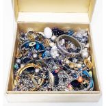 An upholstered box containing a quantity of assorted costume jewellery