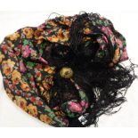 An old floral print silk shawl with fringed edge and large ornate enamelled gilt brass clasp