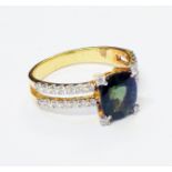 An unmarked high carat yellow metal ring, set with central oval green sapphire with diamond set