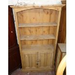 A 3' 3 1/2" pine bookcase with moulded top, three open shelves and pair of panelled cupboard doors