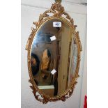 A reproduction decorative gilt metal framed oval wall mirror