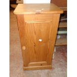 A 15 1/2" waxed pine bedside cabinet enclosed by a panelled door, set on plinth base