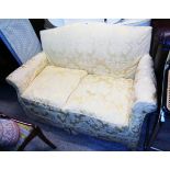 A 4' 8" vintage two seater cottage settee with gold floral fitted cover upholstery, set on castors