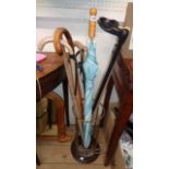 A brassed metal and polished wood stick stand containing a selection of modern sticks and an