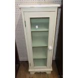 A 11 3/4" painted wood and glazed pedestal cabinet, set on bracket feet