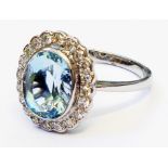 A marked PLAT ring, set with central oval aquamarine within a diamond encrusted border